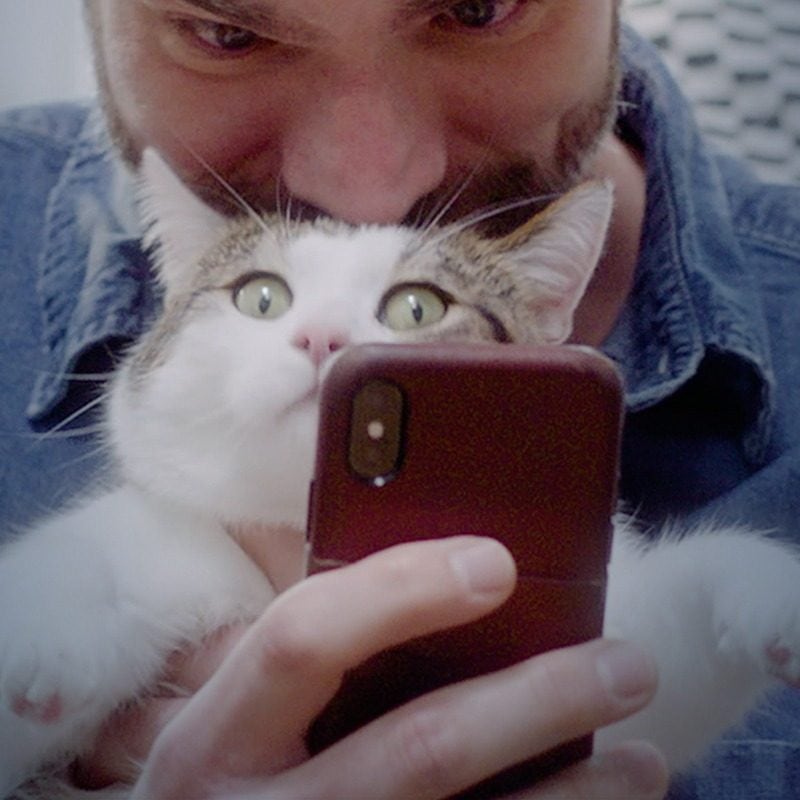 Photo of a cat owner posing with his cat for an Encore Cat Bearder photo
